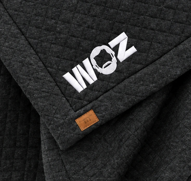 WOZ x TravisMathew Quilted Blanket - corner artwork, cropped from the existing catalog image.