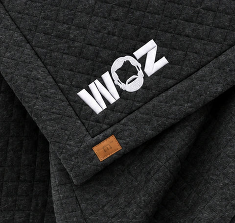 WOZ x TravisMathew Quilted Blanket - corner artwork, cropped from the existing catalog image.