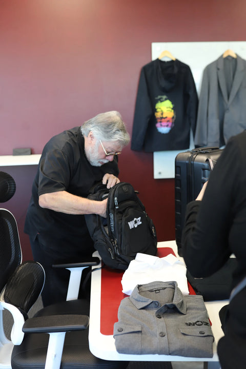 Woz looking inside a black WOZ-branded backpack.