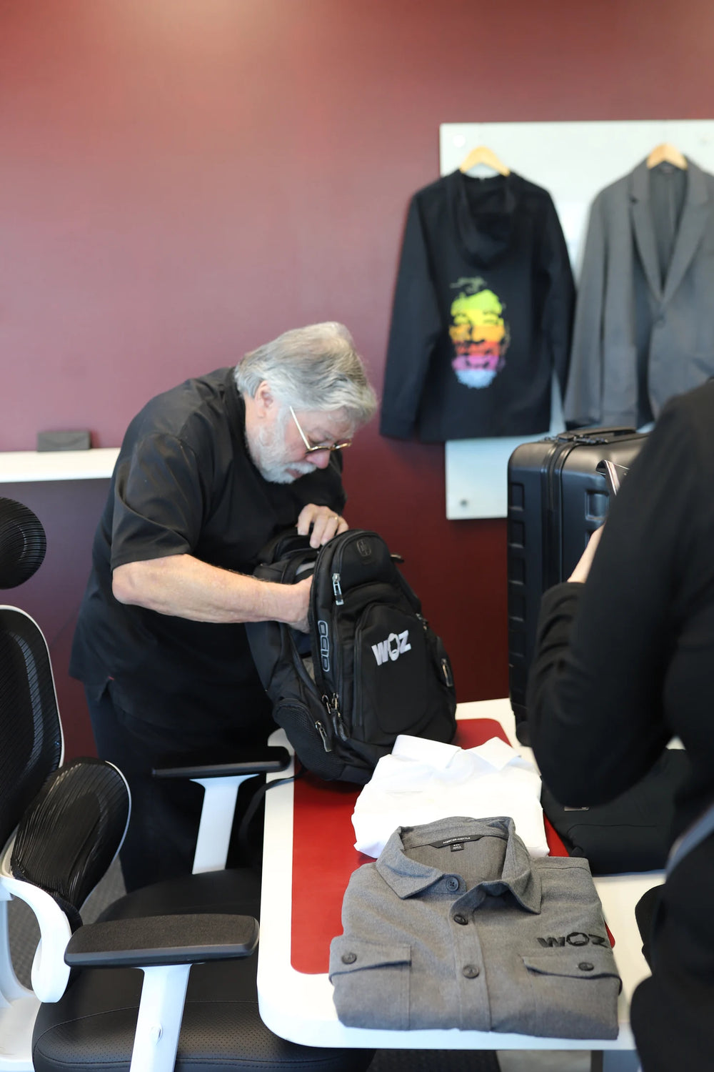 Woz looking inside a black WOZ-branded backpack.