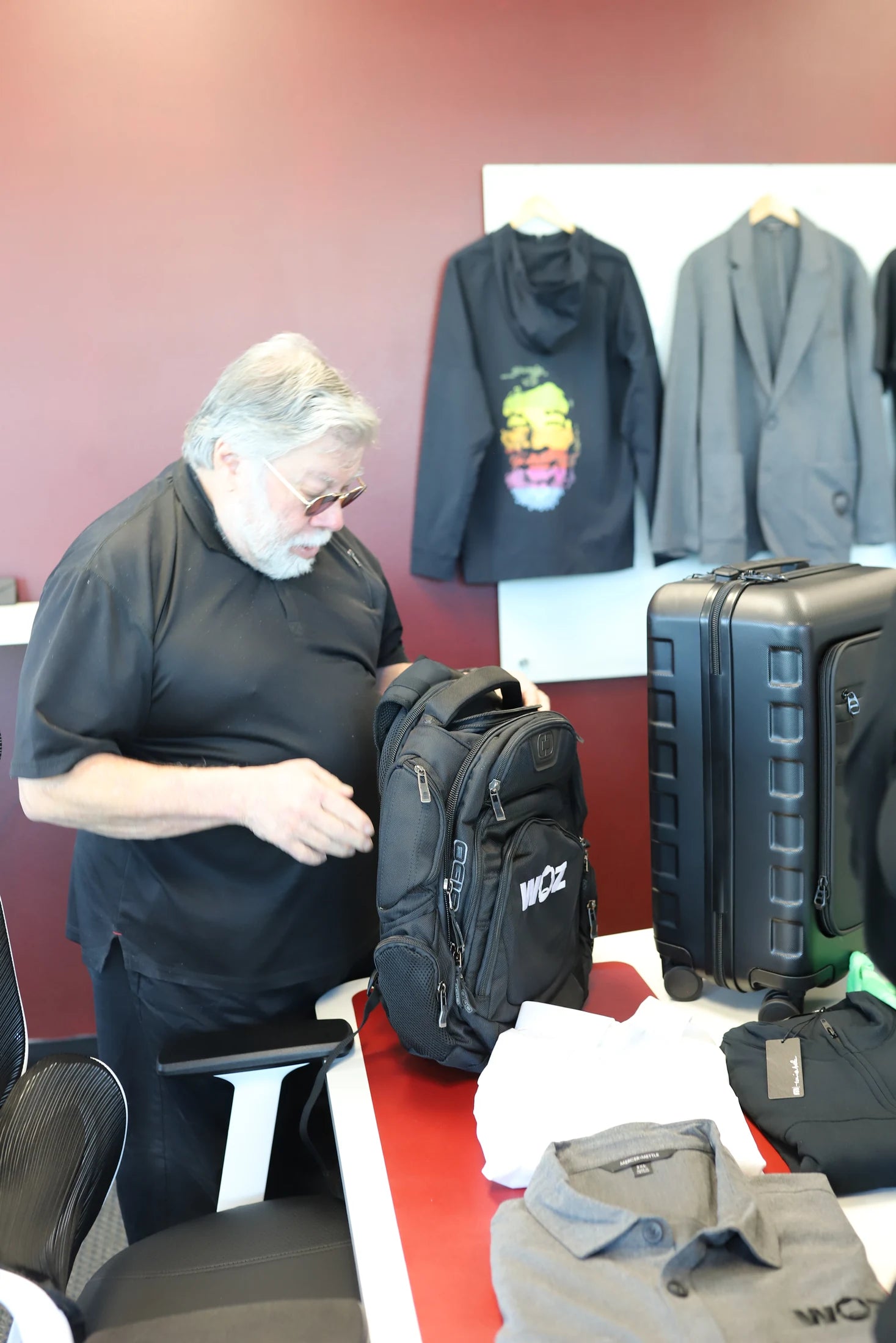 Woz examining a WOZ-branded backpack.