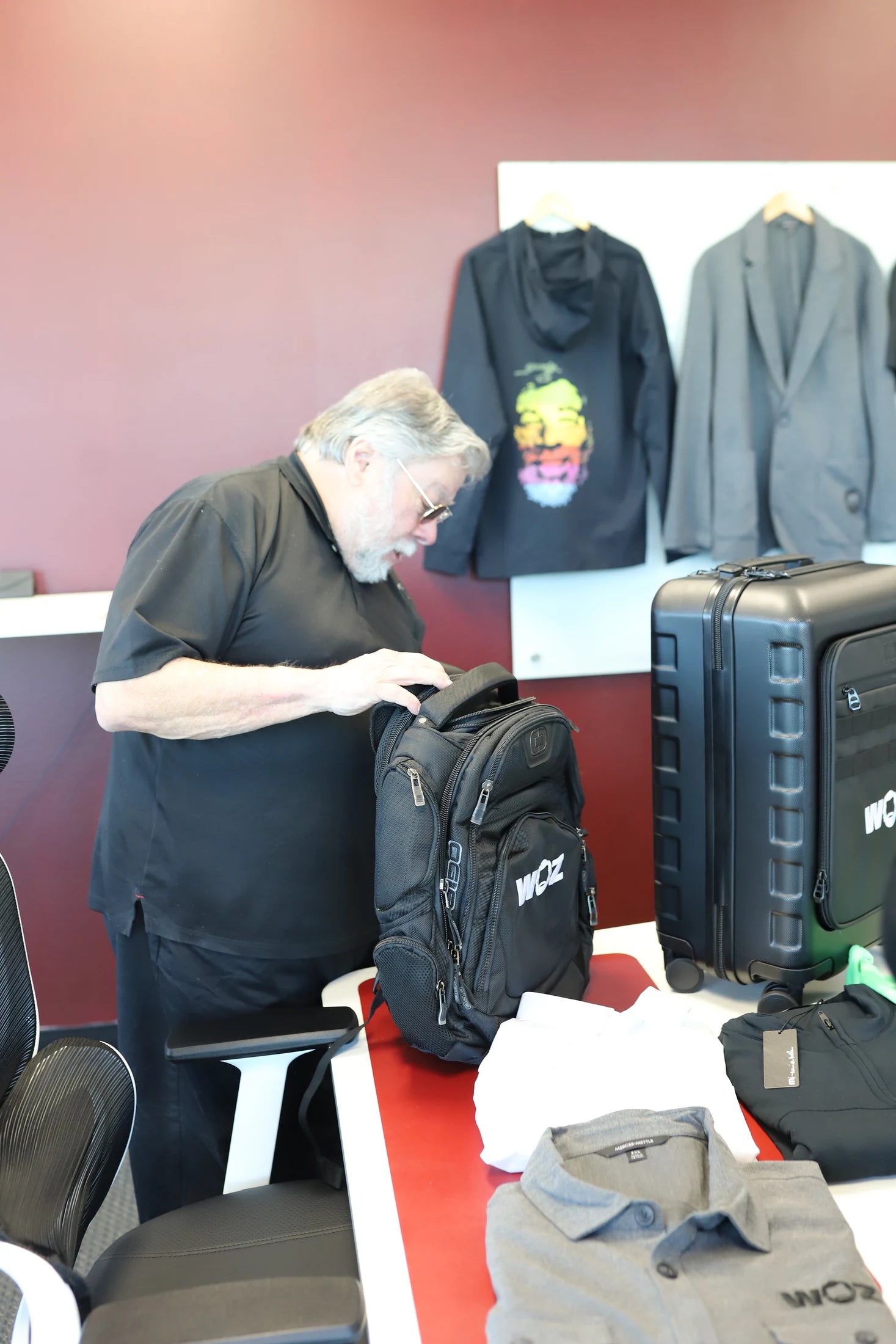 Woz checking the upper compartment of a black WOZ backpack.
