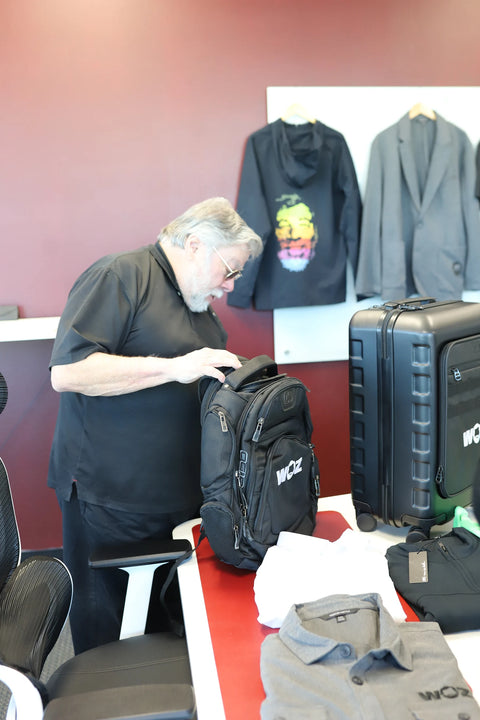 Woz checking the upper compartment of a black WOZ backpack.
